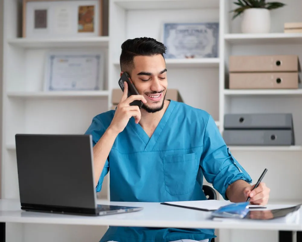 A person speaks on the phone, giving medical front desk Support to the Patient