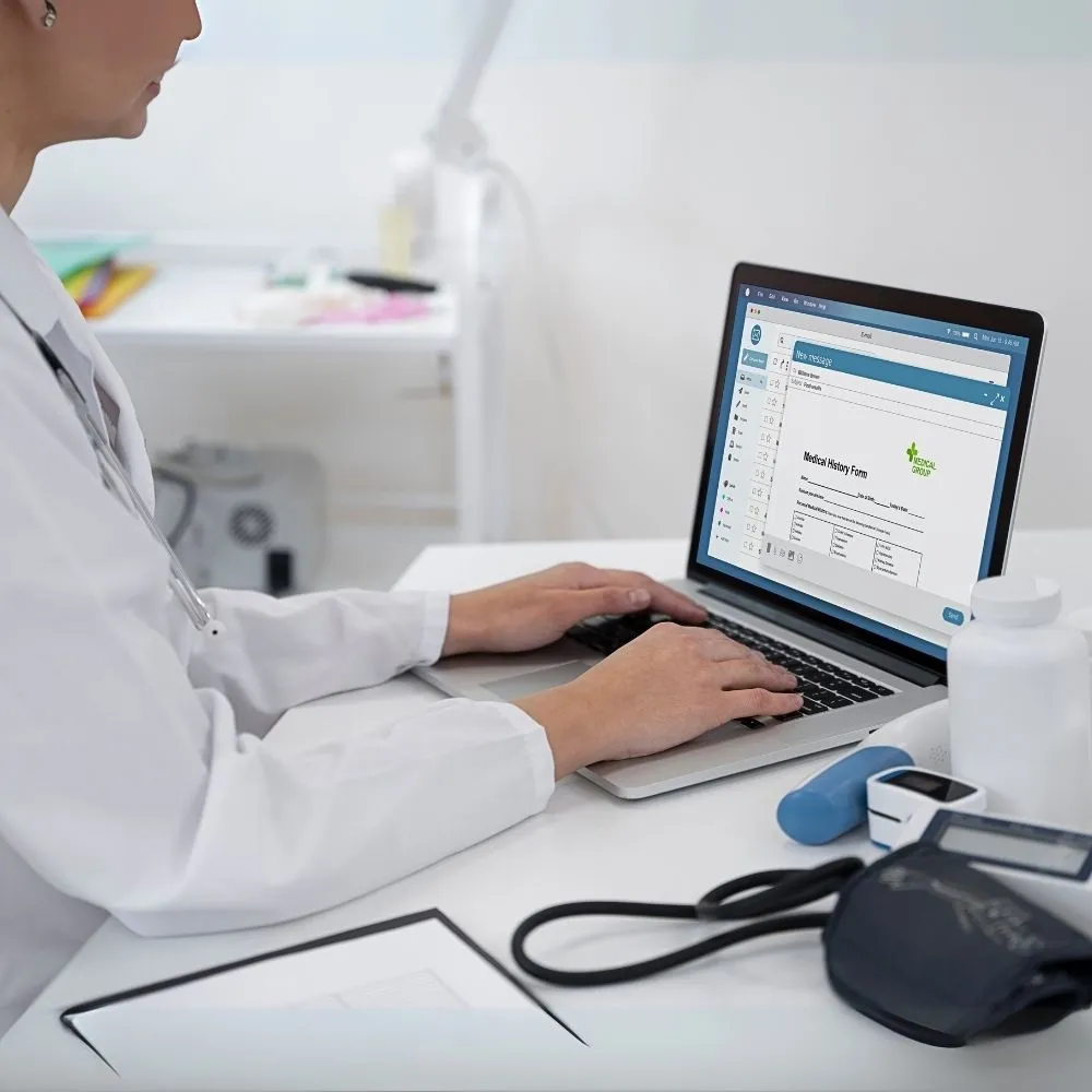 A healthcare professional types on a laptop displaying a medical history form